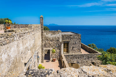 Castle of aragons at ischia. old ruin by sea against blue sky