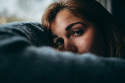 Close-up portrait of woman lying down at home