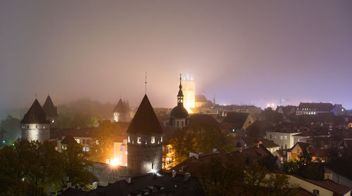 Illuminated buildings in city against sky at night