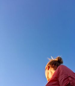 Low angle view of woman against clear blue sky