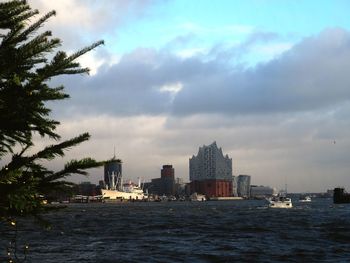 Sea by buildings in city against sky