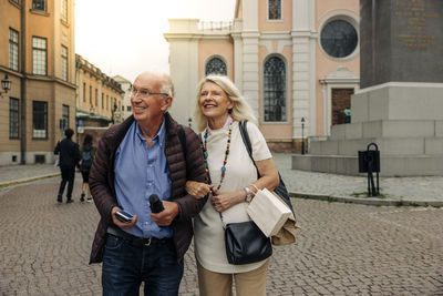 Smiling retired senior couple walking on street in city