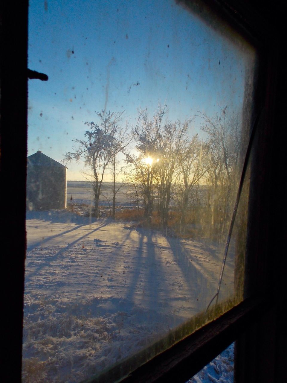 window, glass - material, transparent, indoors, sunset, sky, water, transportation, silhouette, wet, clear sky, vehicle interior, looking through window, tree, built structure, sun, road, car, nature, season