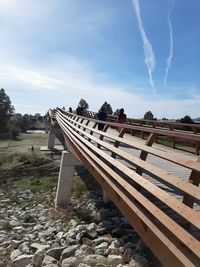 View of empty bench by rocks against sky