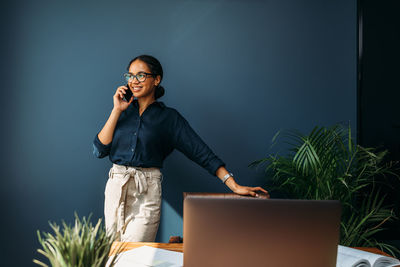 Smiling businesswoman talking on phone while standing in office