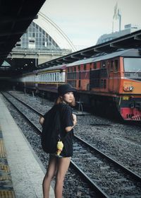 Woman with backpack standing on railroad station platform