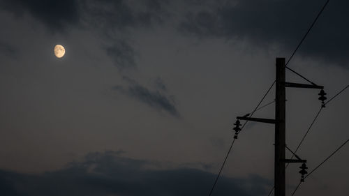 Low angle view of silhouette electricity pylon against sky