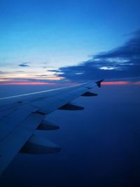 Airplane wing against sky during sunset