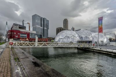 Bridge over river by buildings against sky