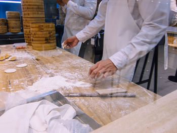 Midsection of chefs preparing food in kitchen seen through glass window 