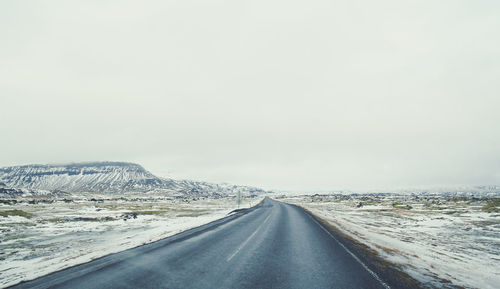 Empty road across snowy field landscape photo