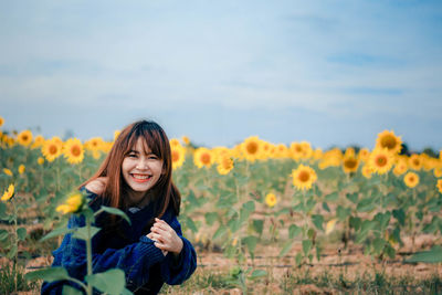 Portrait of smiling young woman with yellow flowers on field