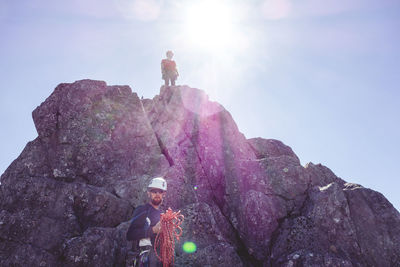 Low angle view of male hikers hiking on mountain against clear sky