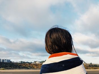 Rear view of woman with umbrella against sky