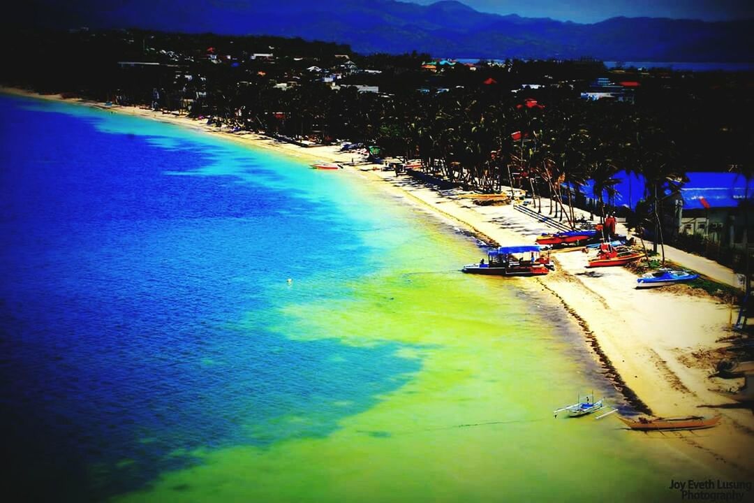 sea, water, blue, high angle view, coastline, beach, transportation, built structure, building exterior, scenics, tranquility, architecture, beauty in nature, nature, shore, tranquil scene, city, nautical vessel, sky, incidental people