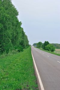 Empty road amidst trees against sky