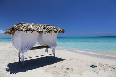 Deck chairs on beach against clear blue sky