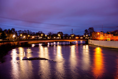 Illuminated bridge over river against sky at night