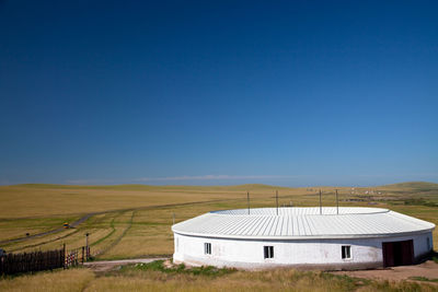 Built structure on field against clear blue sky