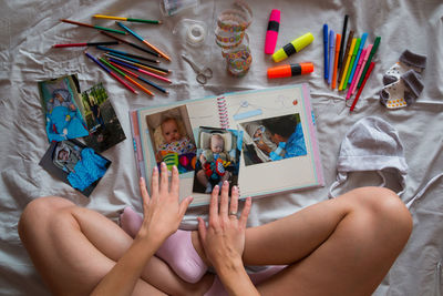 Low section of woman touching photographs on scrapbook by equipment