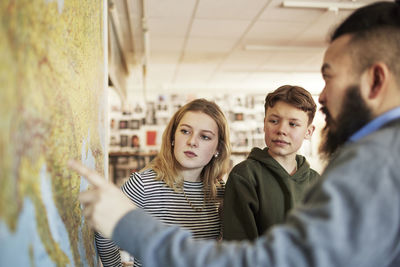 Students and teacher examining map in class