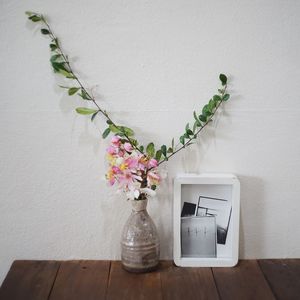 Close-up of white flower vase on table against wall at home