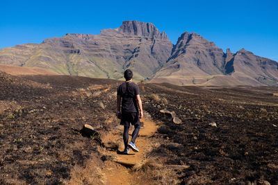 Rear view of man on mountain against blue sky