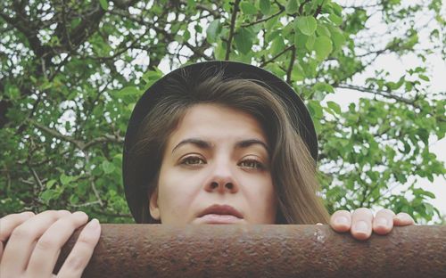 Close-up portrait of young woman against tree