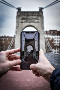 Man photographing through mobile phone in city