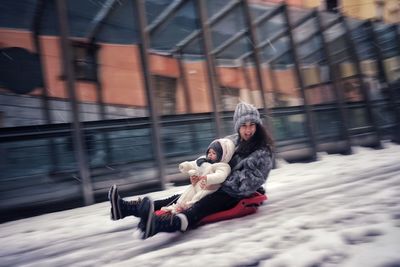 A woman with a baby sliding through the snow with a sled