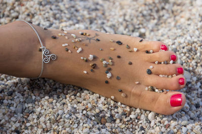 Close-up of woman hand on pebbles at beach