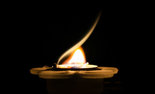 Close-up of lit candle in dark room