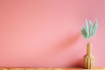 Close-up of pink flower vase against wall