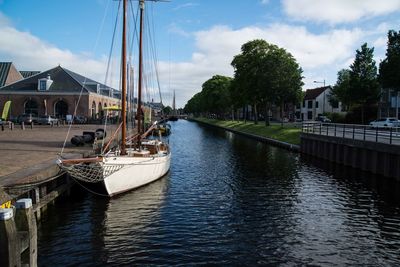 Sailboats moored in river against sky