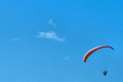 Low angle view of person paragliding against blue sky