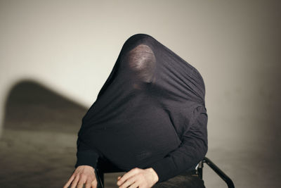 Man sitting on chair against wall