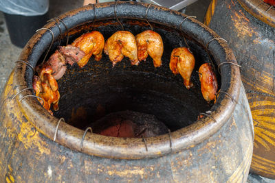 High angle view of chicken thighs hanging and grilling in a barbecue ceramic jar at a restaurant