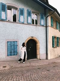 Woman standing by window of building