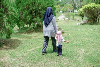 Rear view of woman standing on grassy field