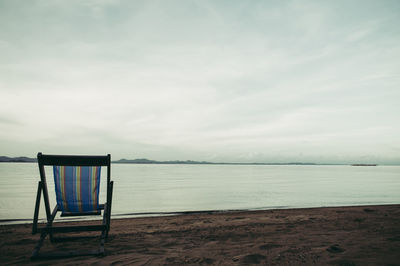 Chair on beach against sky