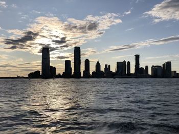 Sea and buildings against sky during sunset
