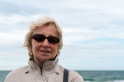 Portrait of woman wearing sunglasses at beach against sky