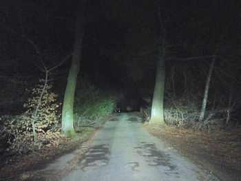 Road amidst trees against sky at night