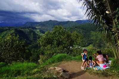 Rear view of people walking on mountain against sky