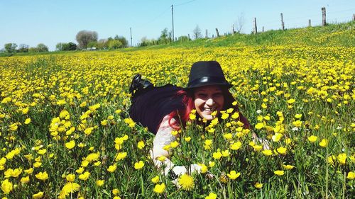 Smiling woman lying in field of yellow flowers