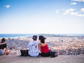 Rear view of woman looking at cityscape against sky