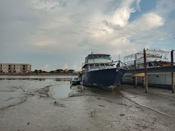 Abandoned ship moored on beach against sky