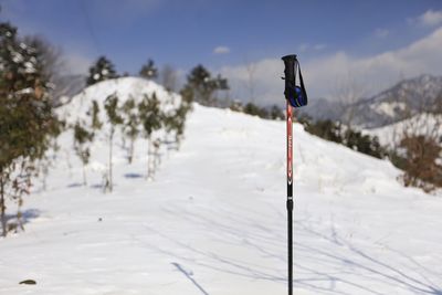 Ski pole on snow covered field against sky