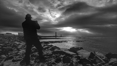 Silhouette woman standing on beach against sky during sunset