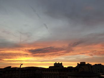 Low angle view of buildings against cloudy sky during sunset